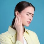 Donna con espressione infastidita che si tocca l'orecchio