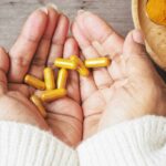 Persona con capsule gialle in mano