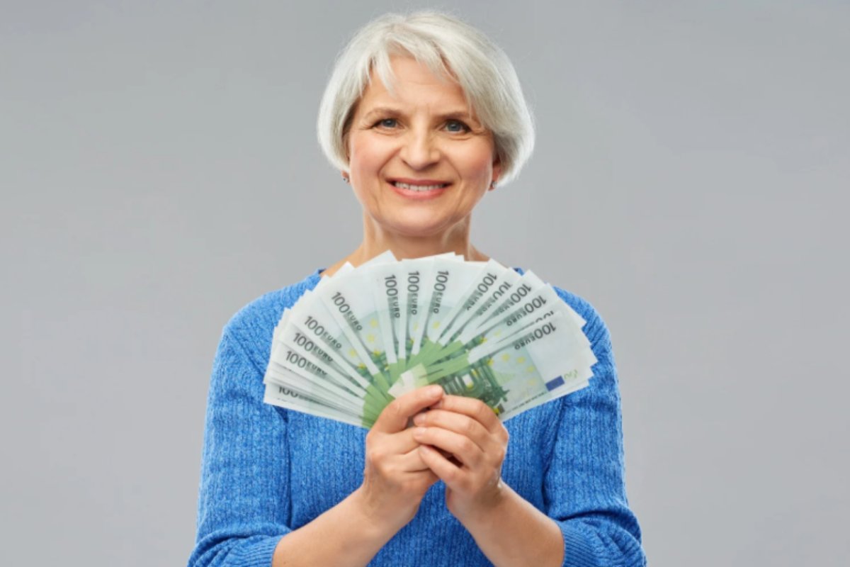 donn anziana sorridente con in mano tante banconote da 100 euro