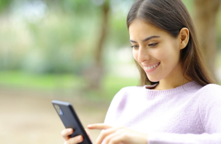donna sorridente che guarda una cosa sul cellulare