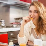 donna che mangia un biscotto in cucina