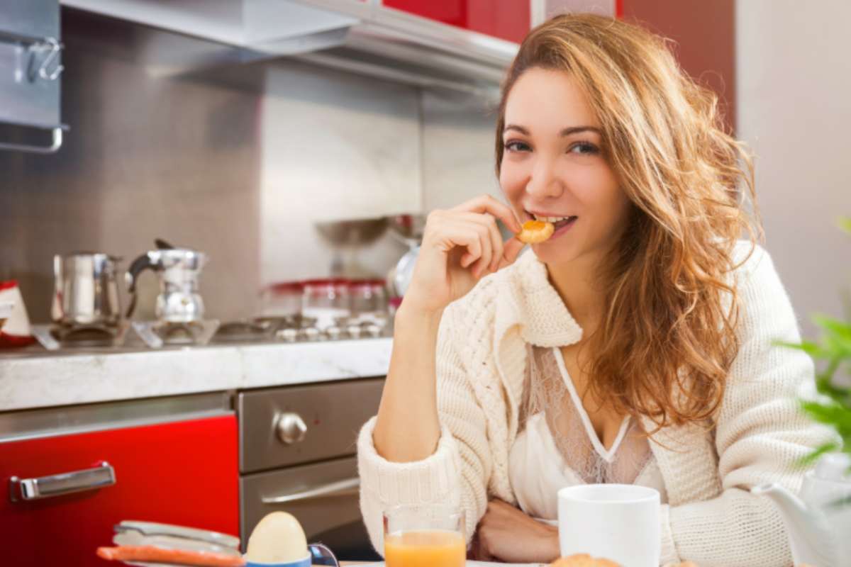 donna che mangia un biscotto in cucina