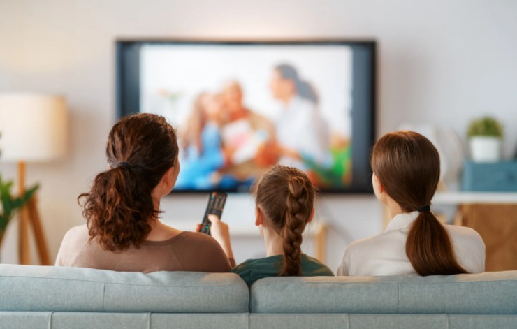 mamma con due figlie sul divano che guardano la tv