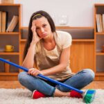 ragazza triste con scopa in mano