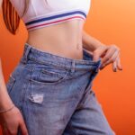 donna magra di profilo che mostra i jeans larghi