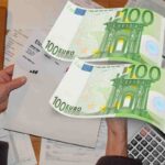 Bollette e due banconote da 100 euro