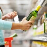 donna al supermercato con in mano una bottiglia di olio