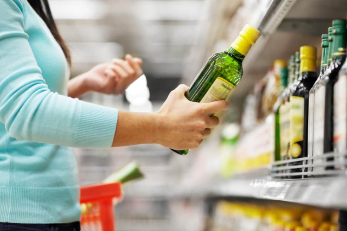 donna al supermercato con in mano una bottiglia di olio