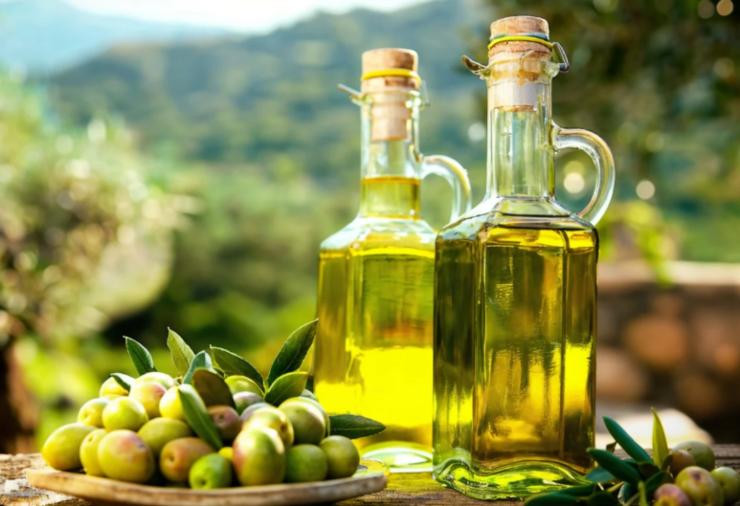 due bottiglie di olio accanto a delle olive verdi
