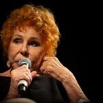 Ornella Vanoni con un microfono su sfondo nero