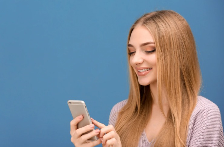 donna sorridente con in mano il cellulare