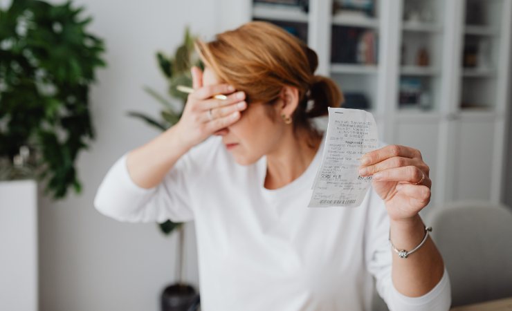 donna preoccupata con bolletta in mano