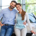 uomo e donna abbracciati e sorridenti appoggiati ad un'auto