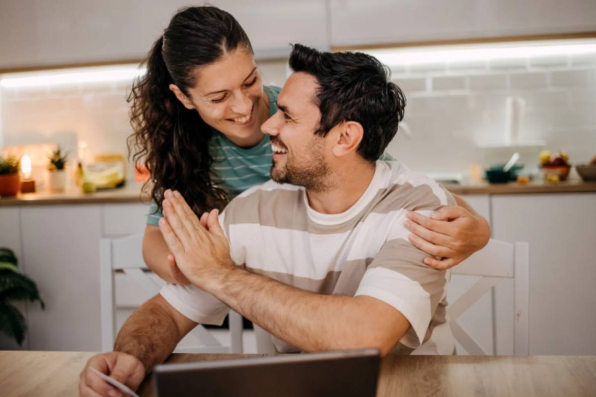 coppia di uomo e donna sorridenti davanti al computer