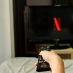 Persona che punta telecomando verso TV con Netflix