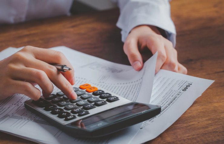 persona che fa i calcoli con la calcolatrice mentre legge dei fogli