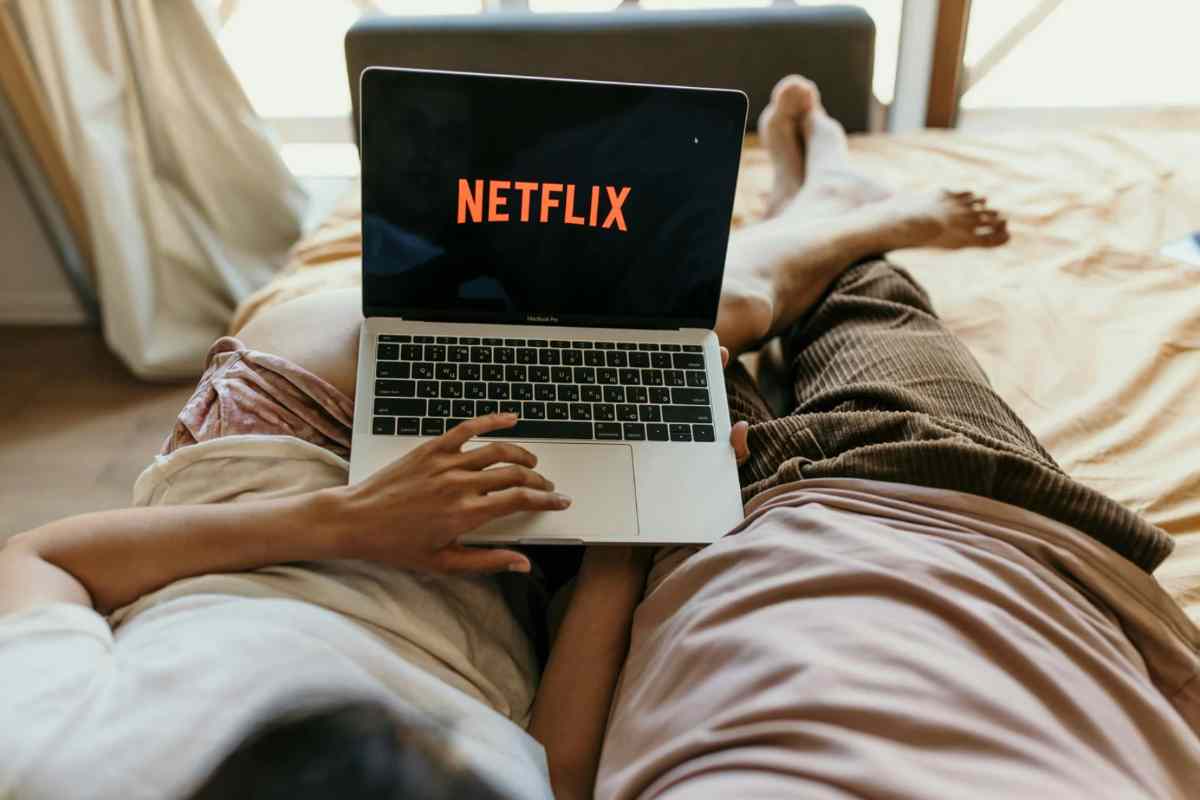 Due persone sdraiate sul letto che guardano Netflix dal pc