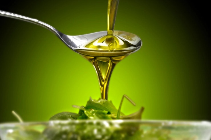 persona che mette l'olio sull'insalata