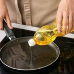 donna che versa dell'olio in una padella