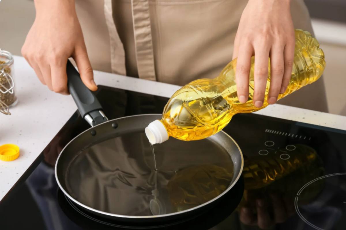 donna che versa dell'olio in una padella