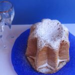 pandoro su un piatto blu con accanto due calici