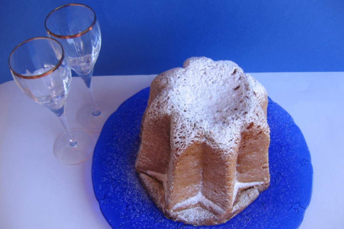 pandoro su un piatto blu con accanto due calici