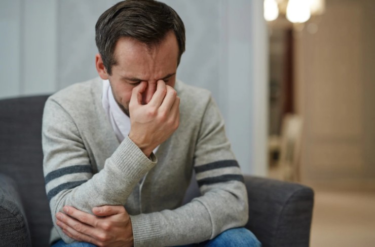 uomo seduto su una poltrona con espressione preoccupata