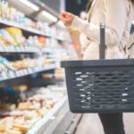 donna al supermercato con il cestino della spesa attaccato al braccio